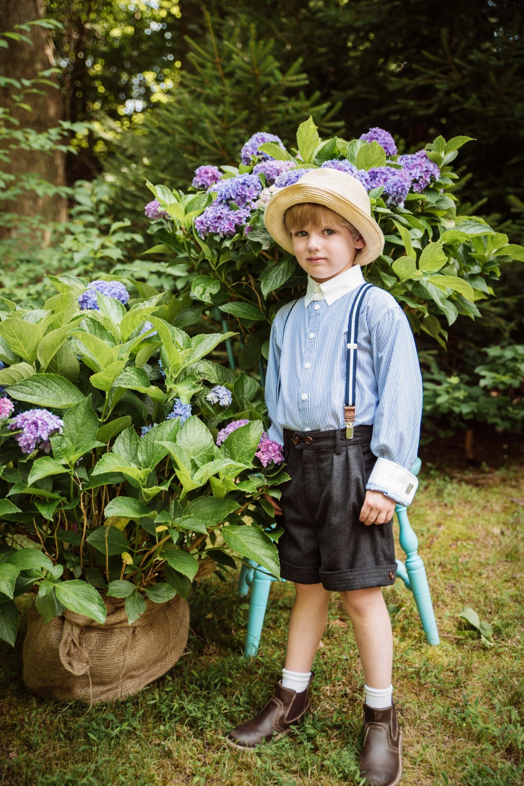 Silhouette enfantine en chemise à fines rayures et chapeau de paille dans un jardin d’hortensias